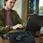 Young man uses laptop, portable storage device on table